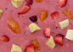 Pink fruit puree with bits of different coloured fruit in it.