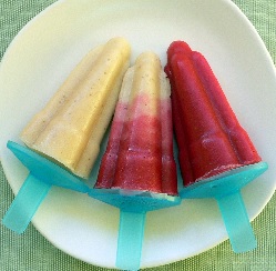 Fruit ice ice lollies on a plate, 1 pale yellow, 1 Tandem and 1 red.