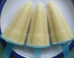 Three light yellow pineapple ice lollies displayed on a plate.